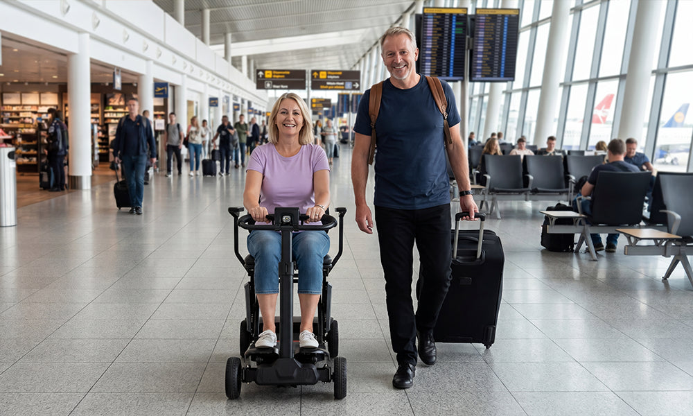 Woman using a folding mobility scooter while traveling through an airport with a companion carrying luggage.